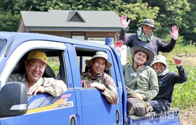 괴산군 계절근로자 프로그램을 통해 배치된 외국인 근로자들이 옥수수밭 앞에서 단체사진을 찍으며 농번기 현장의 활력을 보여주고 있다.